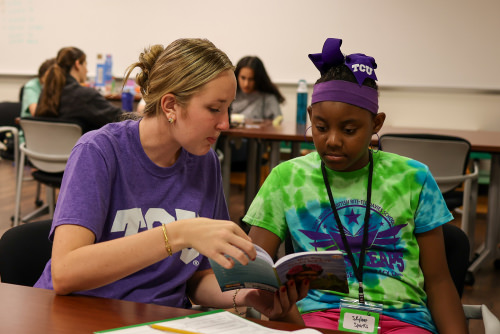 TCU student reading to a youth girl