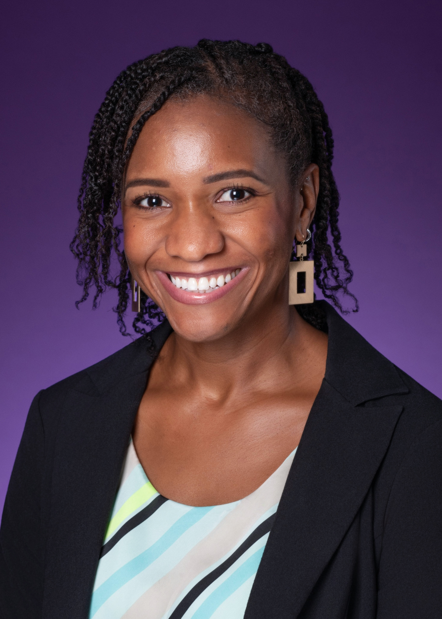 A woman smiling, wearing a blue, green, and black striped shirt with a black blazer, with a purple background