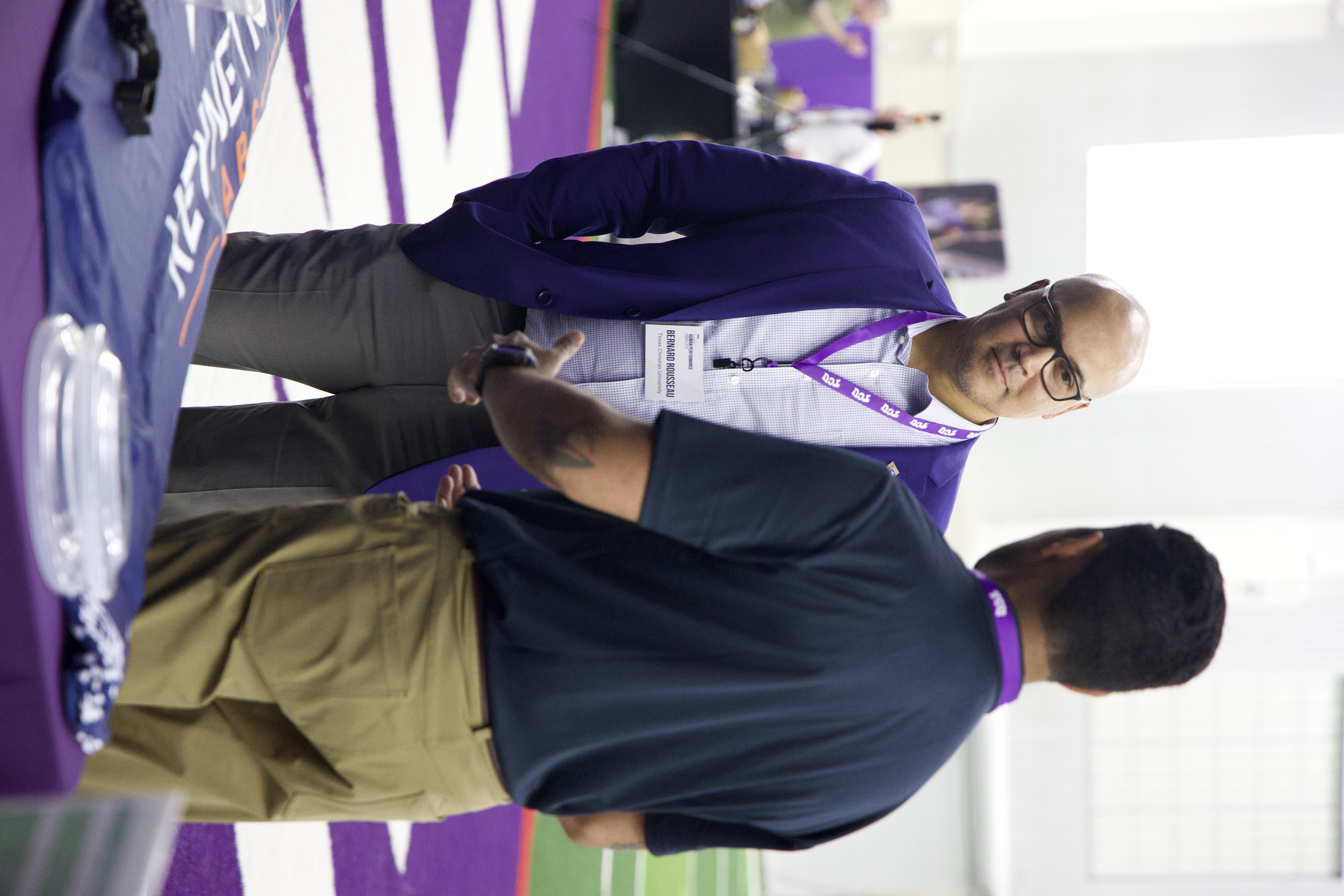 Dr. Bernard Rousseau, incoming dean of Harris College, stands next to a researcher as they discuss wearable data collection devices at the Global Human Performance Forum. 
