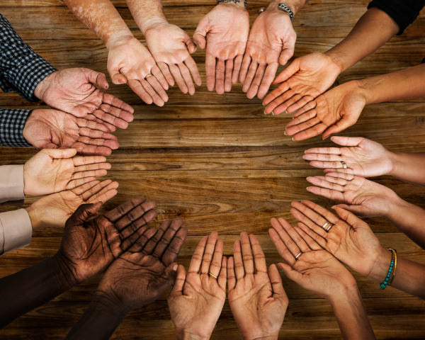 circle of people holding their hands together that have different skin colors