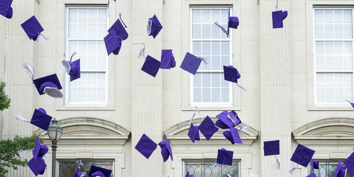 Close up photo of purple graduation caps thrown in the air
