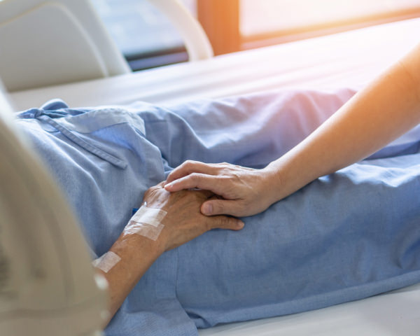 patient lying on hospital bed with nurse holding their hand