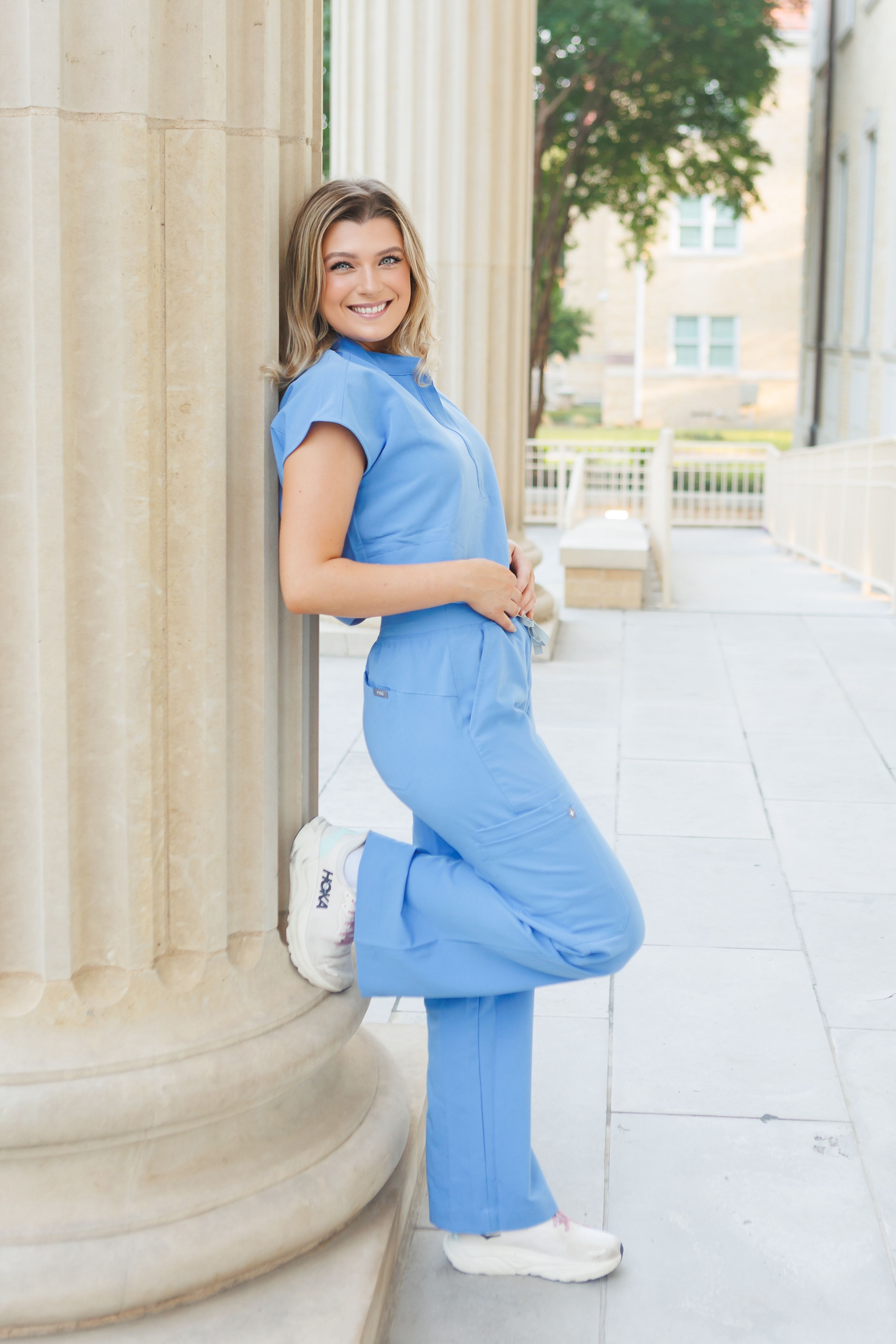 Sara Scott, Class of 2026, poses in her light blue nurse scrubs for senior portraits