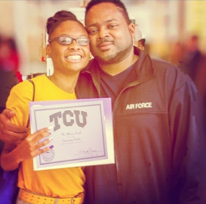 Abriana showing her acceptance to TCU with her dad next to her 