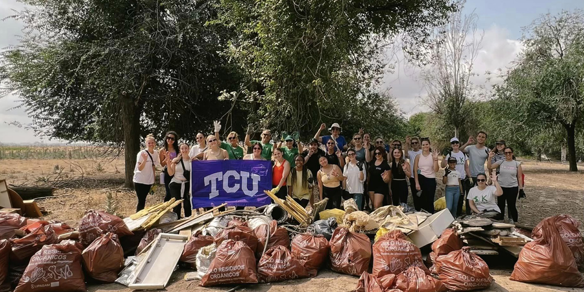 TCU students next to a pile of of trash they picked up in one of their community-based events in Spain