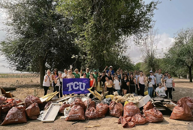 TCU students next to a pile of of trash they picked up in one of their community-based events in Spain
