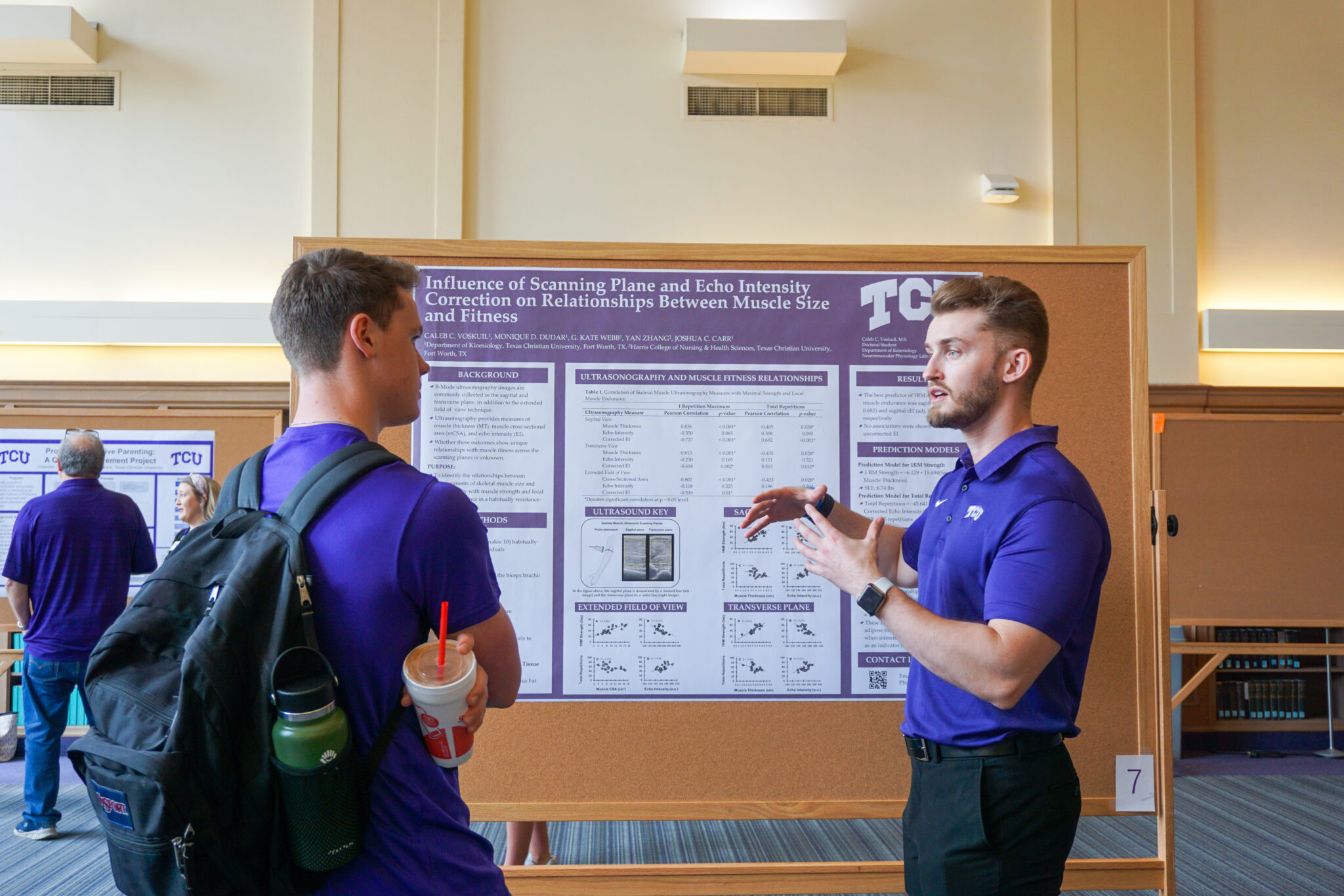 Doctoral student Caleb Voskuil presenting his research poster to another TCU student.